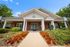 Inviting apartment leasing center featuring a charming brick facade, elegant columns, and vibrant landscaping under a bright blue sky.