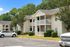 Charming apartment complex with cozy, double-story units, surrounded by lush greenery and ample parking space.