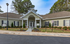 Charming leasing center exterior with classic architecture, surrounded by vibrant greenery and colorful flowers.