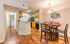 Inviting open-concept kitchen and dining area with modern decor, warm wooden flooring, and stylish wall art.