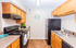 Charming kitchen with warm wood cabinetry, sleek black appliances, and elegant countertops, ideal for cooking enthusiasts.