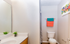 Bright and modern bathroom featuring sleek white fixtures, vibrant towel accents, and a touch of greenery for a refreshing appeal.