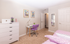 Bright bedroom featuring elegant decor with a cozy workspace, vibrant artwork, and inviting pink bedding.