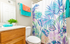 Vibrant bathroom with tropical-themed shower curtain, sleek vanity, and colorful towels adding a lively touch.