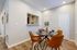 Chic dining area with modern round table, stylish orange chairs, and elegant table settings in a bright, spacious apartment.