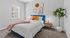 Bright and inviting bedroom with a cozy bed, vibrant accent pillows, stylish decor, and a lush potted plant, perfect for restful evenings.
