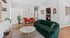 Inviting living room with sleek hardwood floors, a plush green sofa, and stylish orange armchairs surrounded by elegant wall art and vibrant decor.