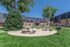 Charming apartment courtyard with lush green lawns, picnic tables, and modern brick buildings, offering a blend of relaxation and community living.