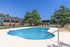 Inviting outdoor pool area with sun loungers, surrounded by modern apartment buildings and lush trees, perfect for relaxation.