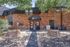 Inviting entrance to a charming apartment building featuring elegant brickwork, lush greenery, and a welcoming pathway.
