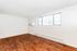 Bright and airy room with elegant hardwood floors and ample natural light from large windows.