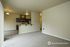 Modern open-concept living space with plush carpet, sleek kitchen featuring stainless steel appliances, and elegant lighting.