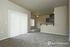 Inviting open-concept living space with plush carpet, large windows, and modern kitchen with bar seating.