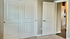 Inviting bedroom with elegant double closet doors, plush carpet, and a glimpse into a modern kitchen.