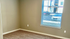 Bright and inviting empty room with plush carpeting and large window overlooking a charming exterior view.