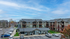 Charming residential complex with modern three-story buildings featuring private balconies and ample parking, set against a picturesque sky backdrop.