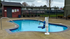 Inviting outdoor swimming pool with modern accessibility lift, surrounded by vibrant landscaping and cozy poolside space.