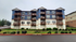 Charming multi-story apartment building with inviting balconies and modern design, set amidst lush greenery.