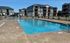 Inviting apartment complex with a sparkling outdoor pool and modern buildings in the background, perfect for leisure and relaxation.