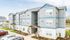 Modern three-story apartment building with sleek gray and blue exterior, ample natural light, and well-maintained landscaping.