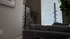 Chic living room corner featuring a modern gray couch, decorative indoor plant, and a minimalist bamboo screen enhancing natural light through blinds.