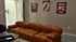 Inviting lounge area with a plush caramel leather sofa, cozy carpet, and cinematic-themed wall art, perfect for relaxation.
