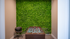 Chic foosball lounge featuring a vibrant green moss wall and a sleek black chair, perfect for relaxation and entertainment.