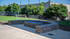 Inviting outdoor sports area with lush green soccer field, volleyball net, and elegant stone fire pit for relaxation.