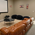 Cozy home theater with a plush leather couch, modern projector, and artistic decor for a comfortable movie-watching experience.