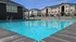 Inviting apartment complex with a sparkling blue pool, poolside relaxation, and modern building backdrop under a clear sky.