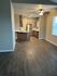 Modern open-plan kitchen with sleek wooden cabinetry, stainless steel appliances, and elegant ceiling fan, featuring rich wood flooring and abundant natural light.