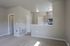 Open-concept living area with modern kitchen and cozy beige carpeting, featuring sleek appliances and bright lighting.