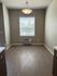 Bright dining area with a large window and modern light fixture, showcasing elegant laminate flooring and a neutral color palette.