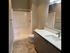 Modern bathroom with elegant vanity, large mirror, and spacious shower area complemented by stylish lighting.