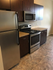 Modern kitchen with sleek stainless steel appliances, dark wood cabinetry, and elegant tiled flooring.