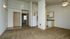 Bright, open-concept living space featuring plush carpeting, modern kitchen with white appliances, and stylish ceiling fan.