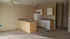 Bright open-plan kitchen with modern appliances and island counter, featuring beige tones and ample natural light.