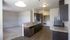 Modern open-concept kitchen featuring sleek dark cabinets, granite countertops, and stainless steel appliances next to a carpeted living area.