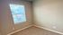 Bright and cozy room with soft carpet flooring and a large window allowing natural light.