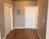 Inviting apartment entrance with sleek wood flooring, modern white doors, and a neutral color palette for a fresh, contemporary look.