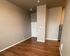Modern apartment entryway with elegant hardwood flooring and high ceiling, featuring a sleek stainless steel refrigerator tucked into the corner.
