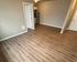Contemporary apartment interior showcasing sleek wood flooring, neutral walls, and a cozy kitchenette area.