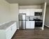 Modern kitchen with sleek white cabinetry, stainless steel appliances, and elegant granite countertops on wood flooring.