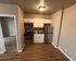 Cozy apartment kitchen with modern stainless steel appliances, sleek cabinetry, and warm wood flooring.