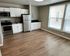 Modern kitchen with sleek stainless steel appliances, elegant white cabinetry, spacious open layout, and large sunlit windows.