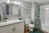 Elegant bathroom with stylish decor featuring a large mirror, granite countertop, and vibrant botanical shower curtain, creating a serene oasis.
