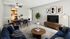 Elegantly staged living and dining area featuring a stylish navy sofa, modern dining set, and minimalist decor with vibrant green plant accents.