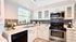 Beautifully designed kitchen with modern stainless steel appliances, chic gray subway tile backsplash, and elegant white cabinetry. Sunlit space enhanced with houseplants and stylish decor, perfect for culinary delights.