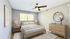 Inviting bedroom with a cozy bed, modern ceiling fan, and stylish wooden furniture, creating a serene and welcoming atmosphere.