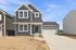Modern two-story home with dark siding and inviting front porch, featuring large windows and a spacious attached garage.
